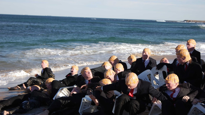 People in Trump masks and suits spilling off plastic chairs and into the ocean.