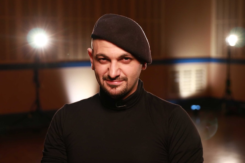 A man in a beret poses for a photo in a studio