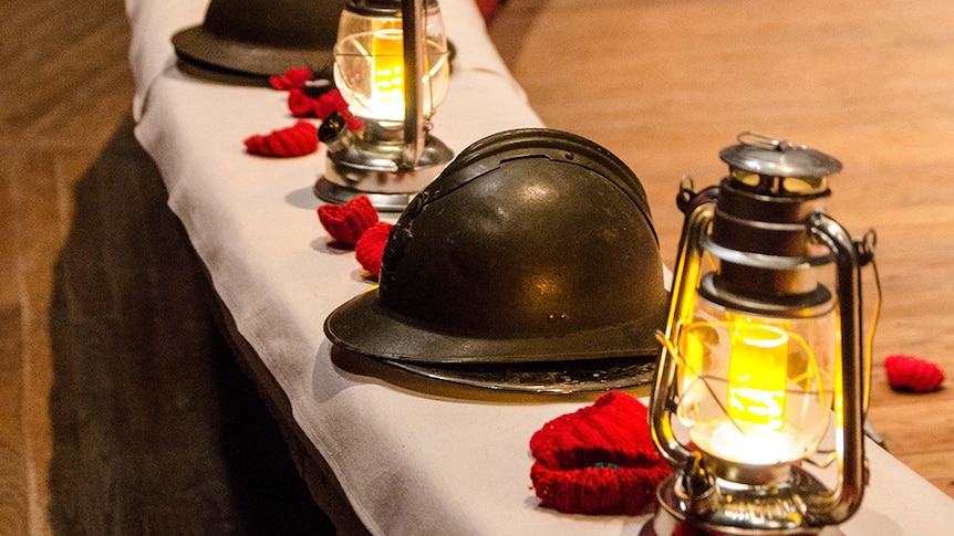 A photo of a rounded table set with helmets from WWI, lanterns and crocheted poppies.