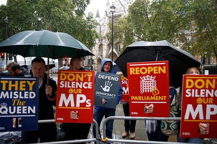 Protesters hold signs calling for Parliament to be reopened and for MPs to be unsilenced outside court.