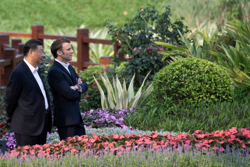 Xi Jinping and Emmanuel Macron stand side-by-side in a garden in Guangzhou