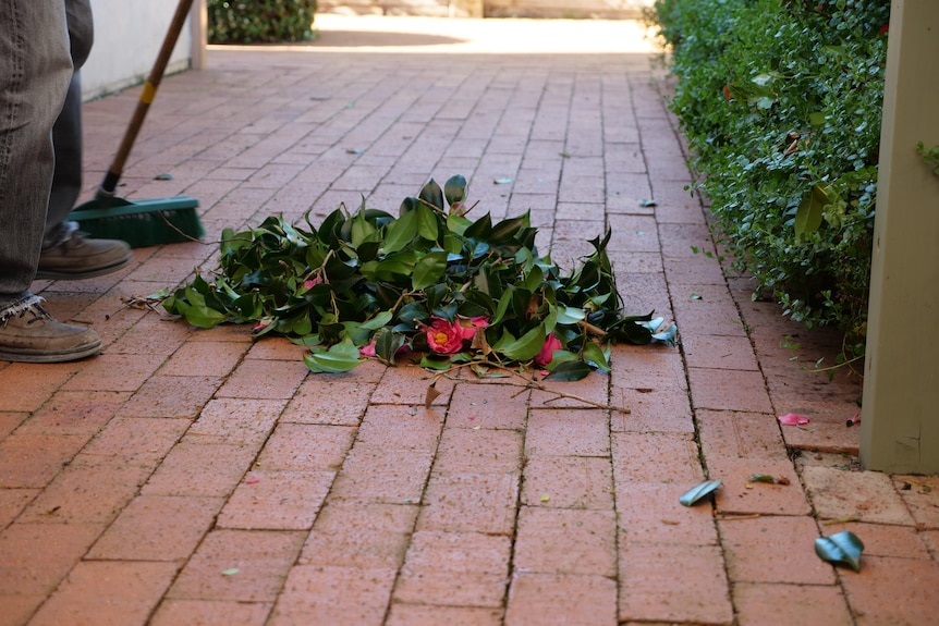 A pile of leaves and flowers on a red brick pathway in a backyard