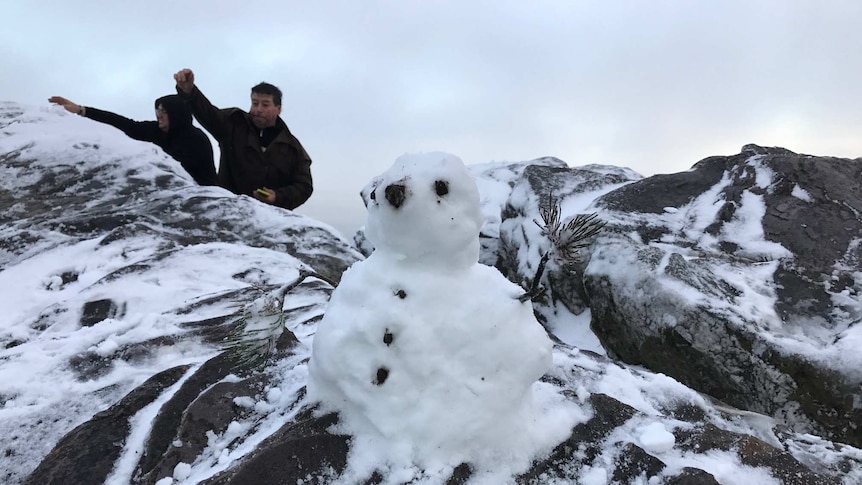 A snow man on Bluff Knoll with a couple of locals in the background enjoying the snow.