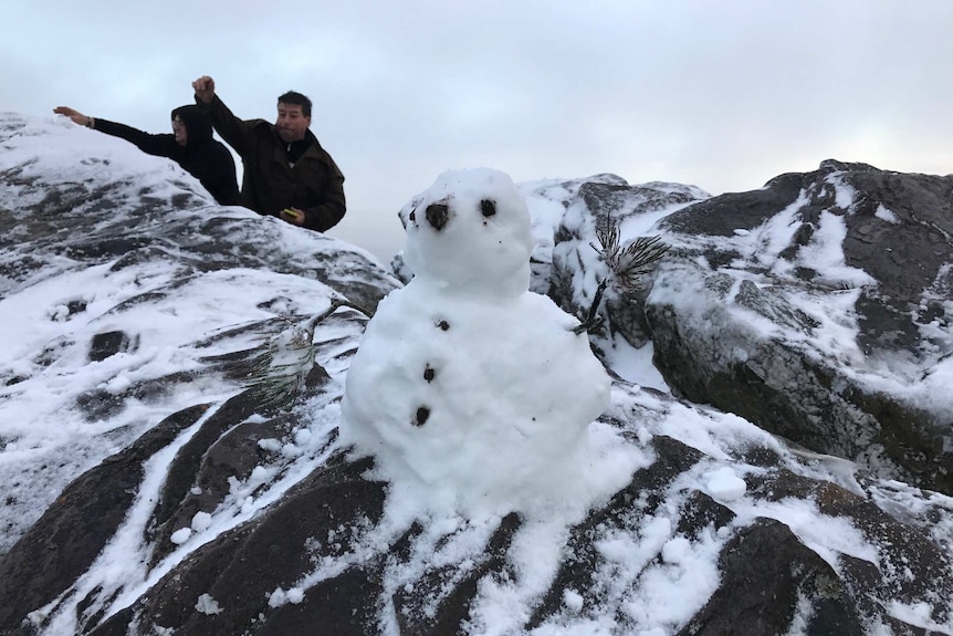 A snow man on Bluff Knoll with a couple of locals in the background enjoying the snow.