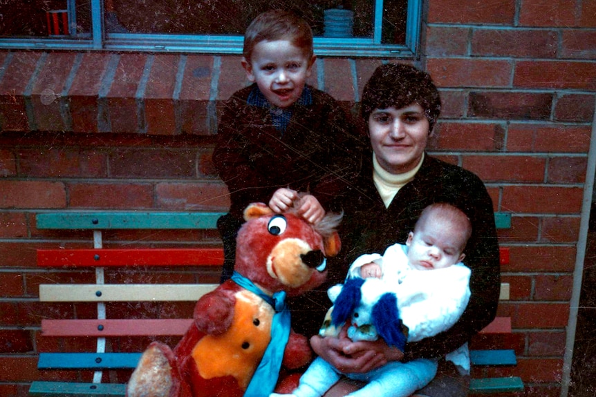 A young Maria James sits with her two sons, both young children.