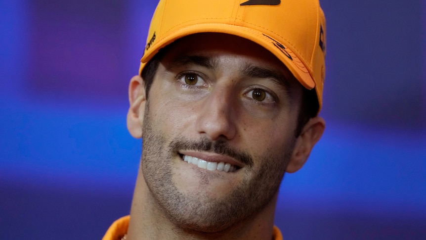 F1 driver Daniel Ricciardo bites his lip while wearing a McLaren cap.