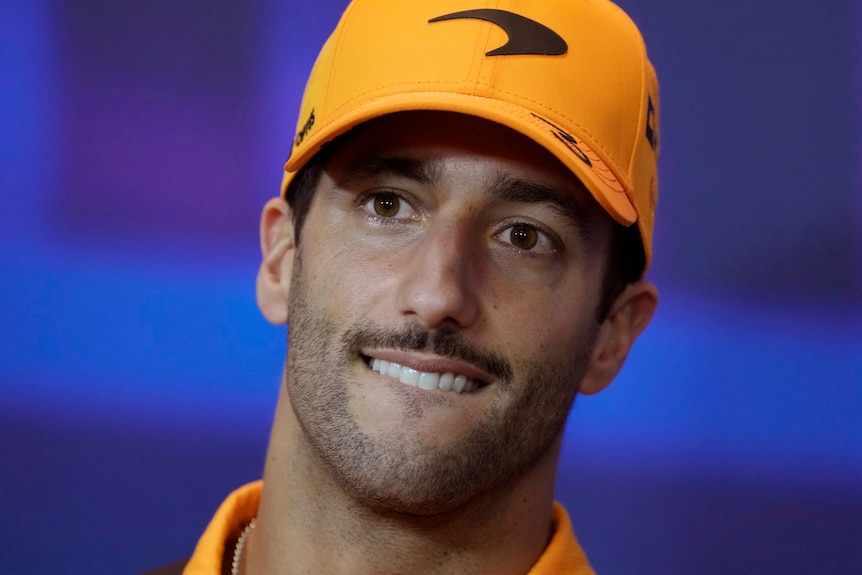 F1 driver Daniel Ricciardo bites his lip while wearing a McLaren cap.