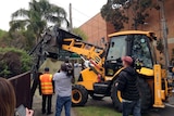 Council machinery lifts the front gate of the Hells Angels clubhouse at Fairfield in Melbourne.