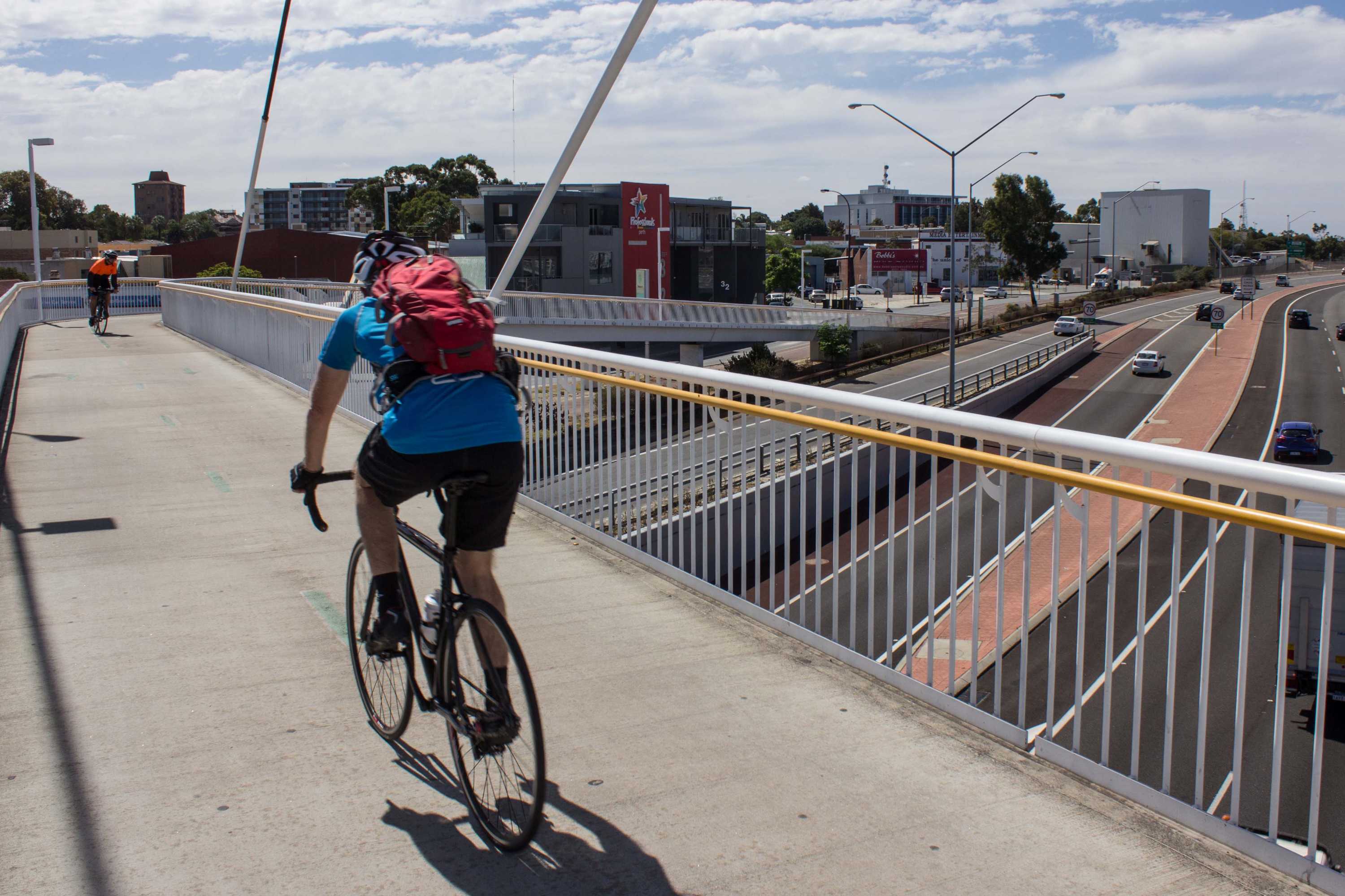 Two cyclists on a shared path at Claisebrook train station, above the Graham Farmer freeway in East Perth