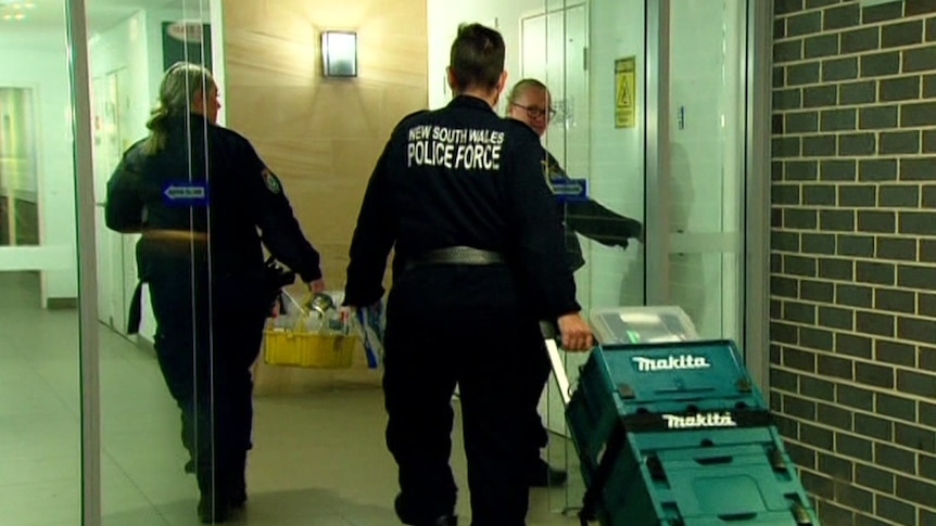 Three police walk through glass doors