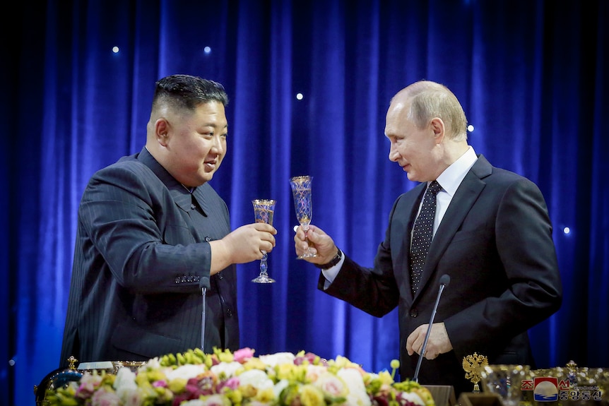 Vladimir Putin and Kim Jong Un toasting champagne floats and smiling at each other 