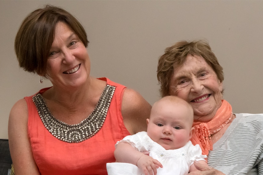 A photo shows two smiling women, once of them holding a young baby