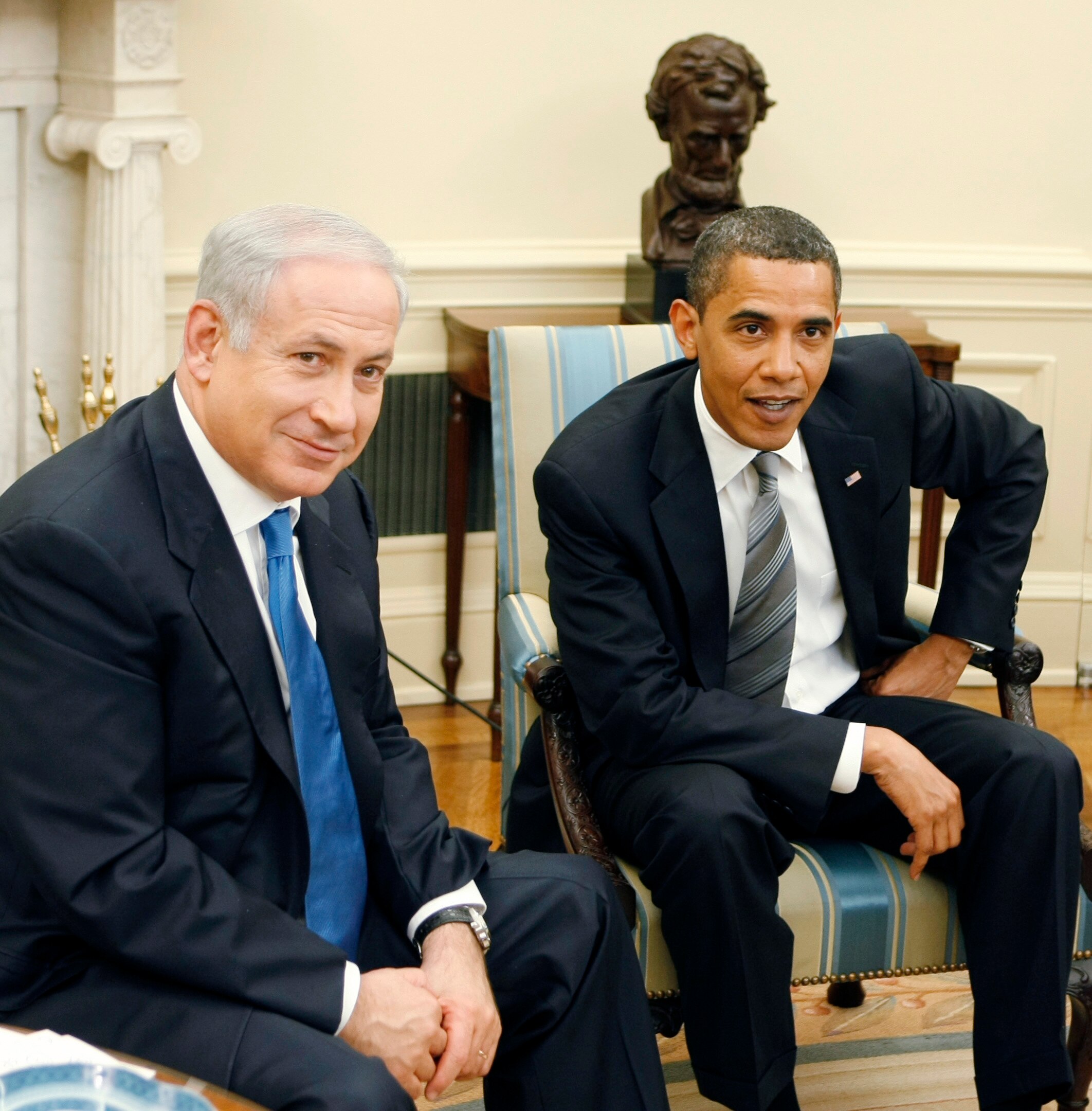 Benjamin Netanyahu sits on a chair in the oval office next to Barack Obama.