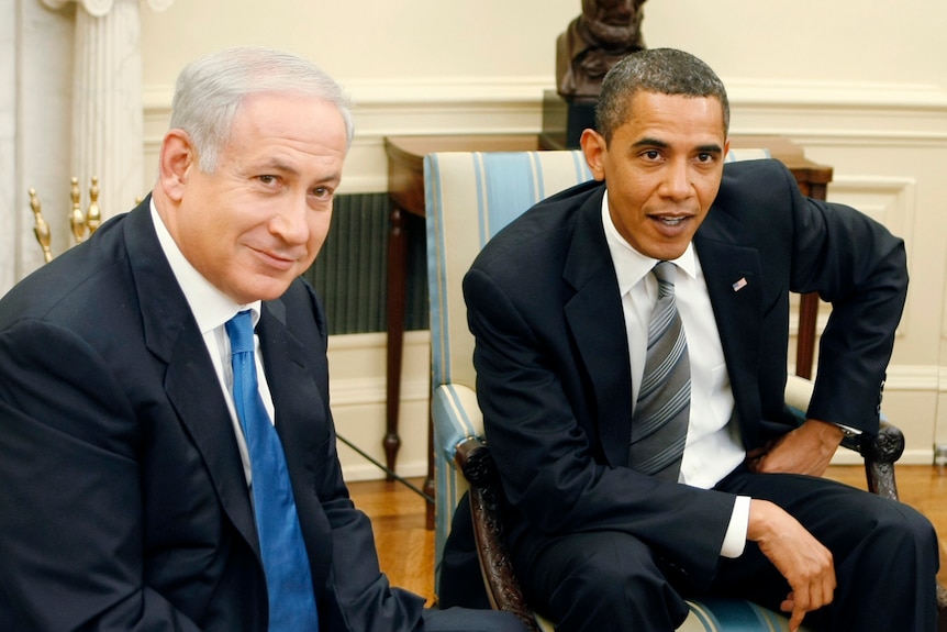 Benjamin Netanyahu sits on a chair in the oval office next to Barack Obama.