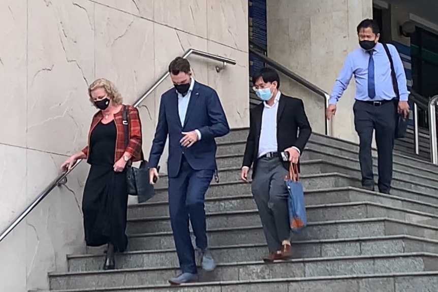 Four people on court steps in business attire. 