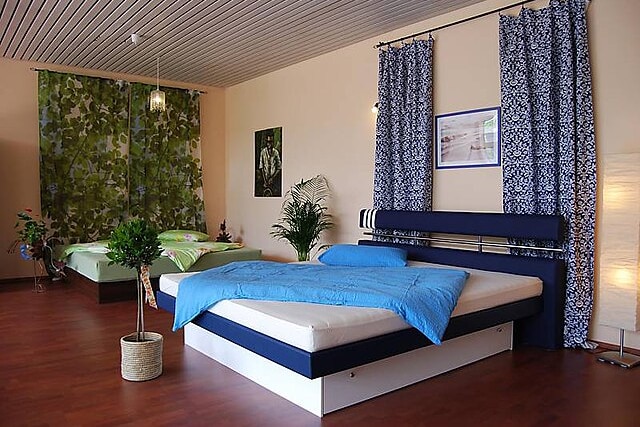 Two water beds, one styled in green and one styled in bed , in a showroom with indoor plants.
