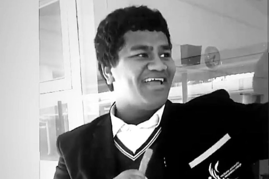 A black and white photo of a teenage boy in a school uniform.