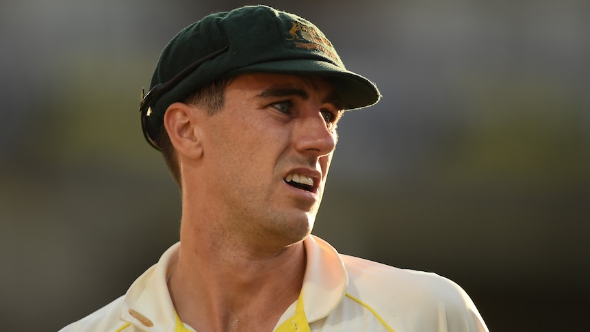 An Australian male Test cricketer looks to his left during a match.