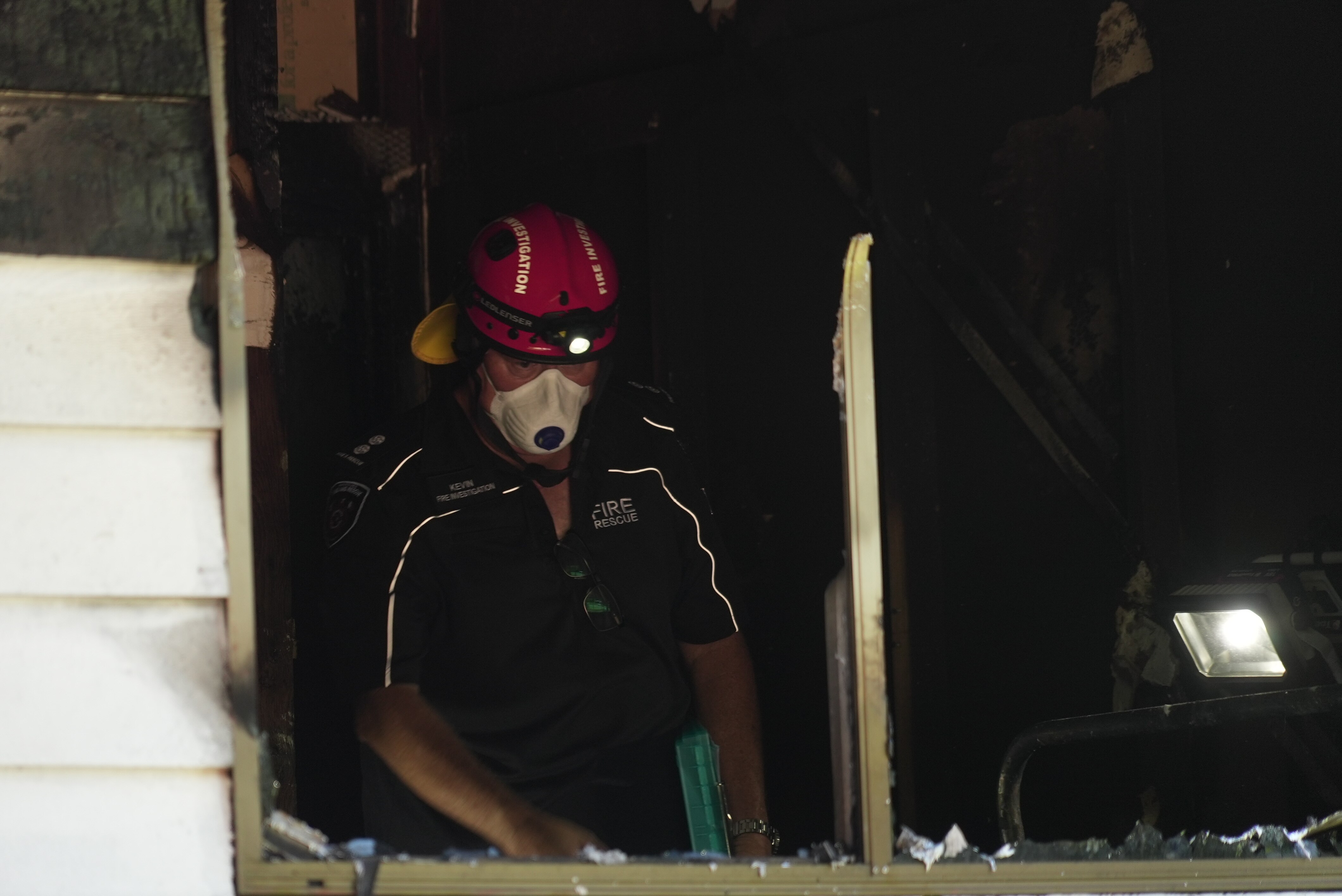 Hombre en la ventana de una casa con casco y mascarilla respiratoria
