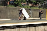 Man pushes a fridge on a trolley along the platform at Bown Hills train station.