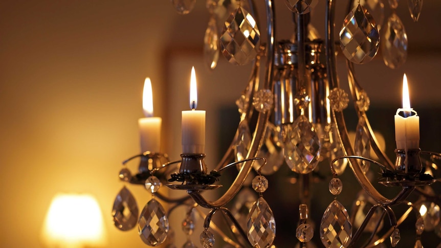 A close-up of candles burning on a crystal chandelier.