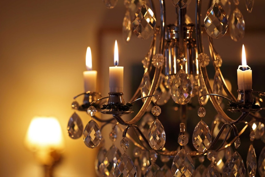 A close-up of candles burning on a crystal chandelier.