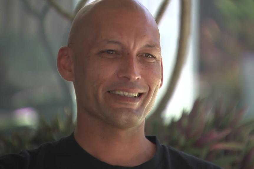 A bald man smiles 