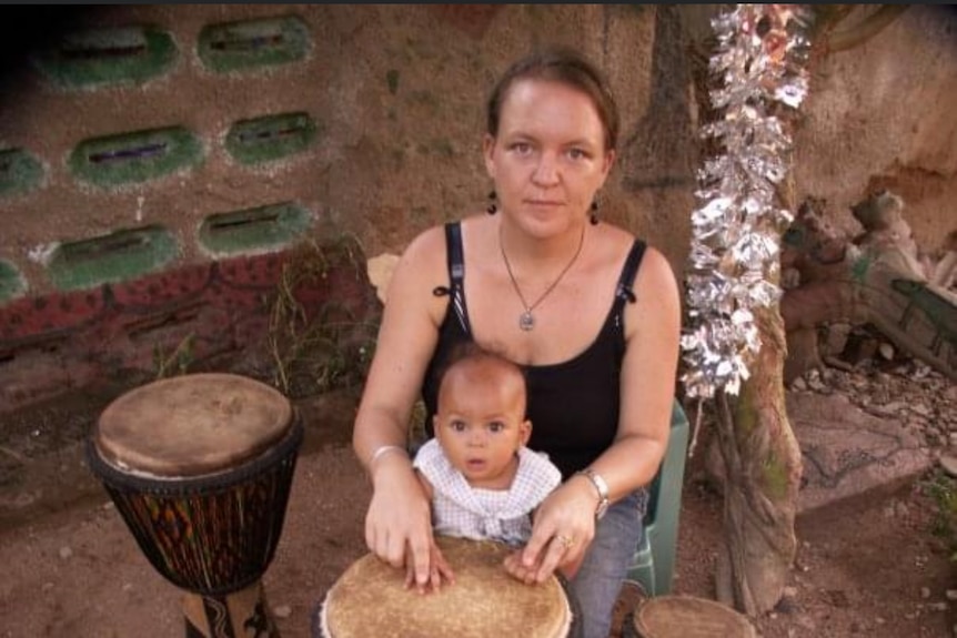 A woman with a small child playing a drum