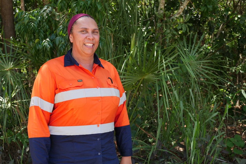 A woman standing front of ferns in firefighting gear