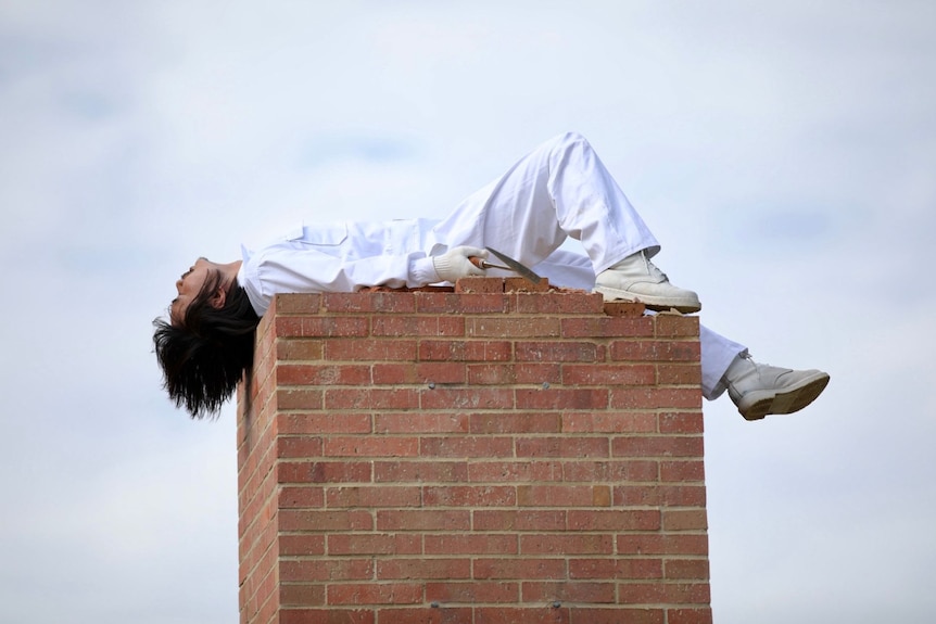 A man sprawls on his back atop a podium of stacked bricks.