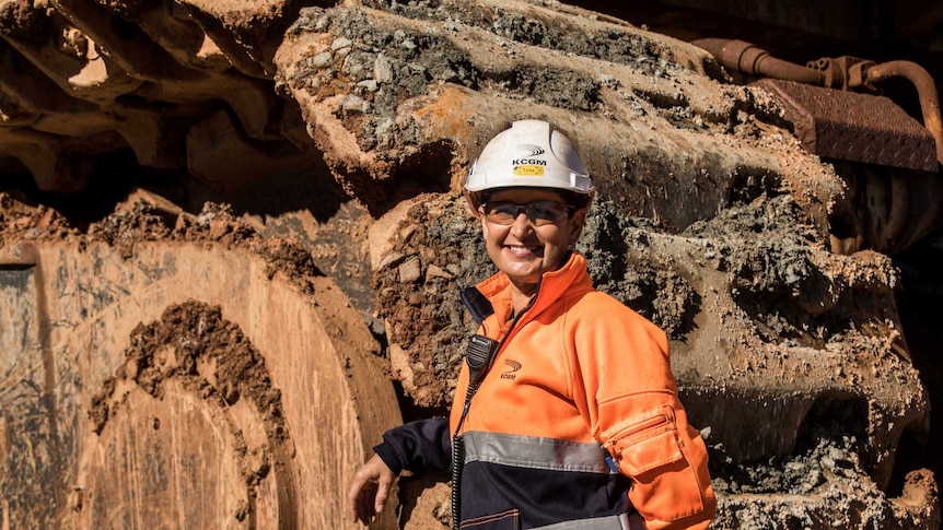 Female mine worker standing in front of machinery in mine