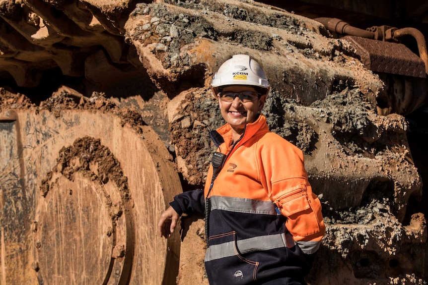 Female mine worker standing in front of machinery in mine