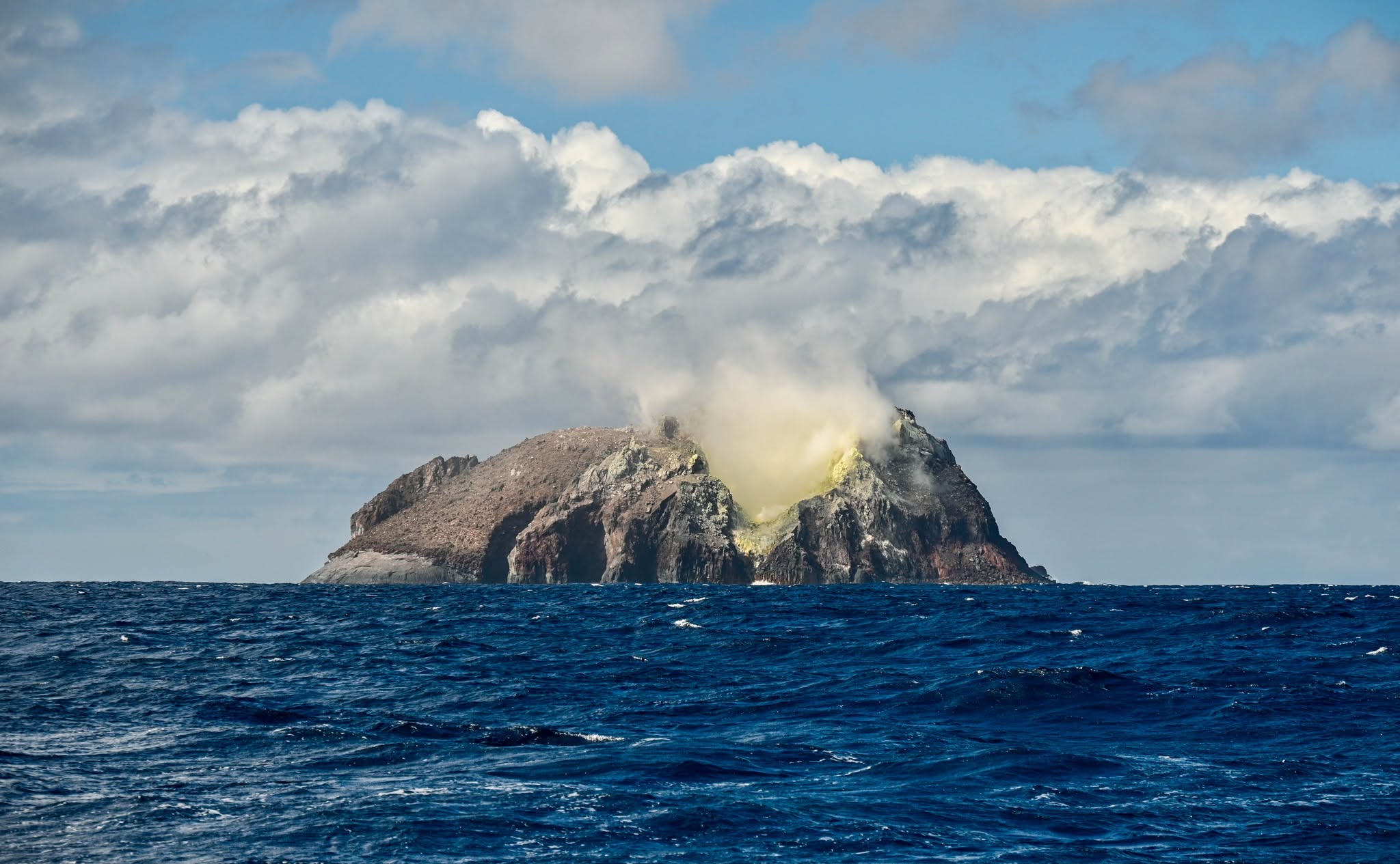 A volcanic island emits Sulphur in the Pacific Ocean. 