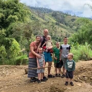 A family stand on a road in a tropical rainforest