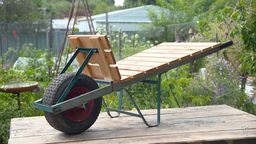 Wheelbarrow that has been converted to a timber-lined garden cart.
