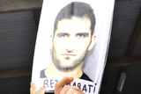 An asylum seeker in Delta compound holds aloft a picture of slain asylum seeker Reza Berati.