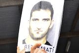 An asylum seeker in Delta compound holds aloft a picture of slain asylum seeker Reza Barati.