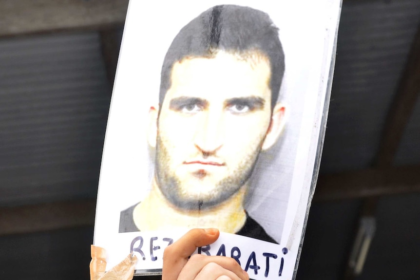 An asylum seeker in Delta compound holds aloft a picture of slain asylum seeker Reza Barati.