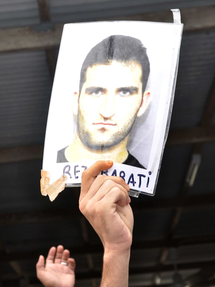 An asylum seeker holds a photo of Reza Barati.