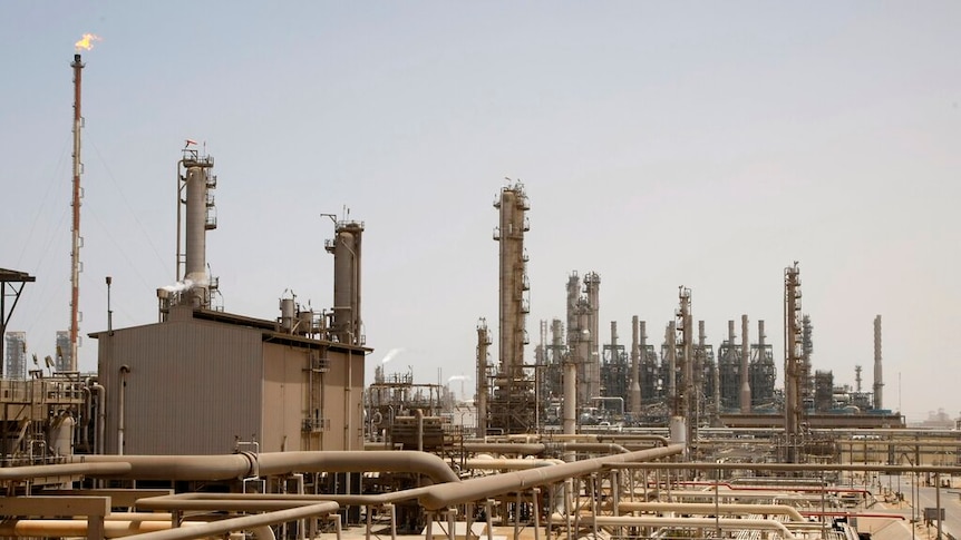 On a clear day, you view a Saudi Arabian oil facility with a myriad of pipes and towers.