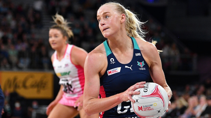 A Melbourne Vixens Super Netball players holds the ball with two hands.