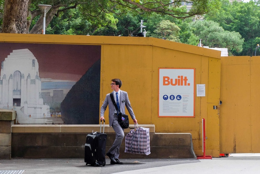 Mormon missionary in suit holding suitcase and bag.