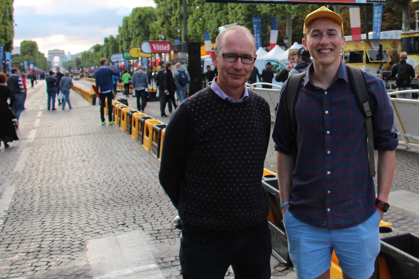 Two men stand on the sidelines of the Tour De France