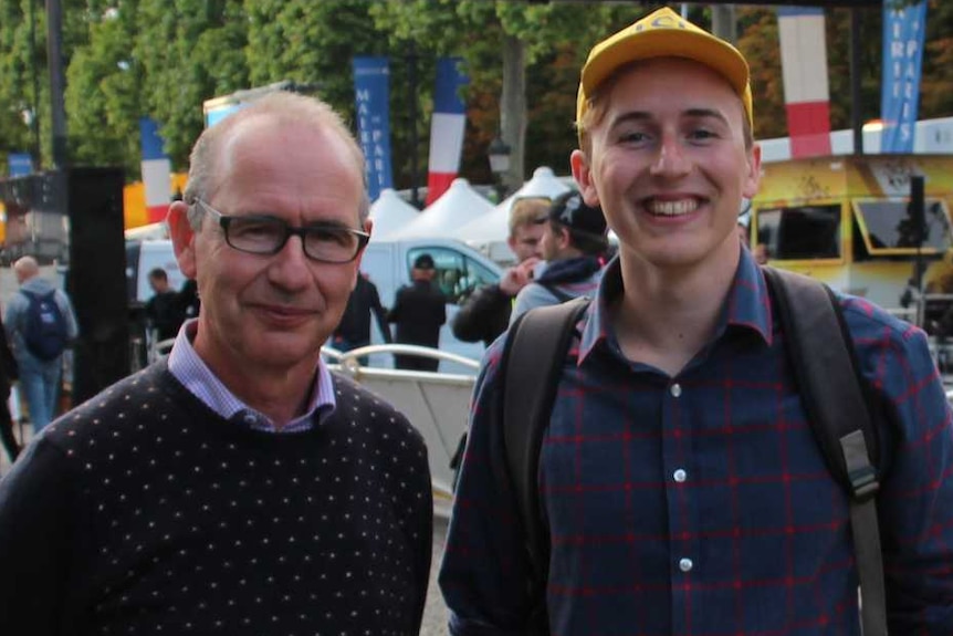 Two men stand on the sidelines of the Tour De France