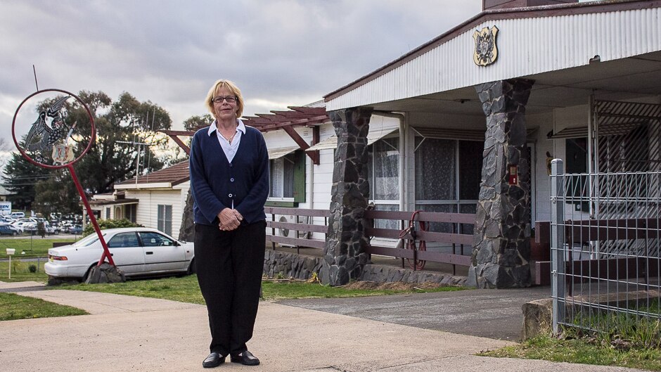 A woman stands outside a house with german style trimmings