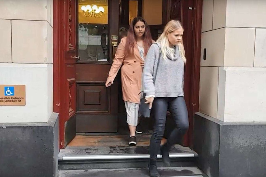 Young women exit a court building.