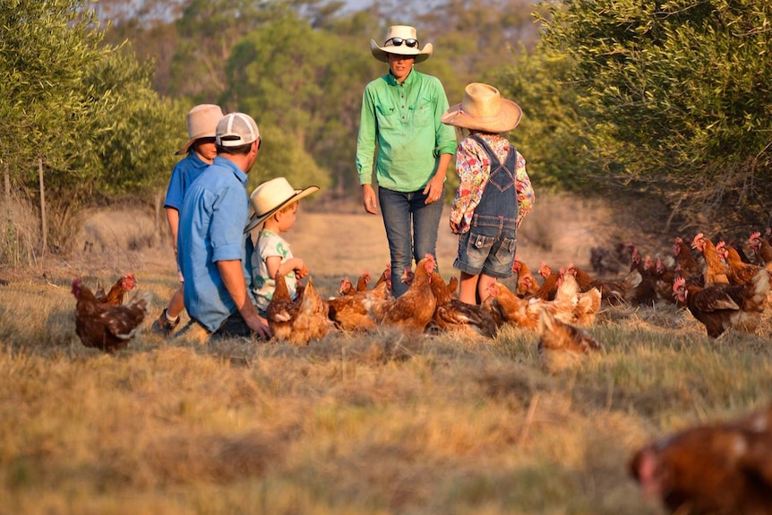 The Birch family - a man, woman and three children, with some of their chickens in a field.