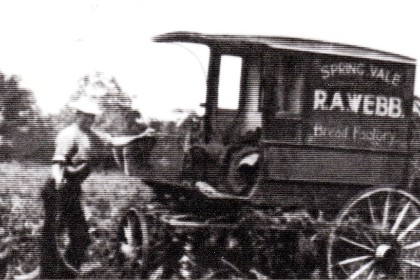 A black and white photo from the 1930s of a man with a bakery cart