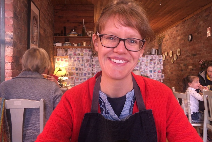 Yackandandah cafe owner Lauren Salathiel smiles at camera inside a cafe setting