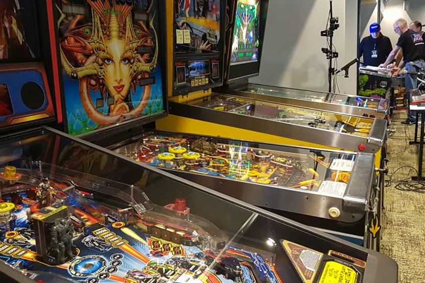 Pinball machines lined up against a wall.